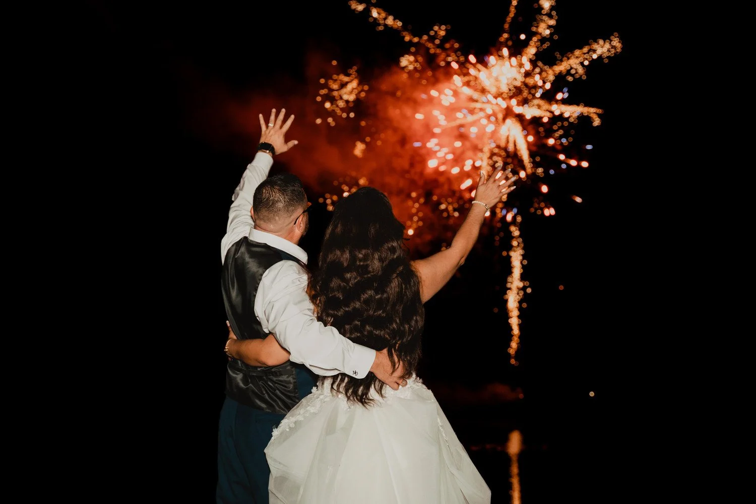 Couple at lakeside, fireworks over lake