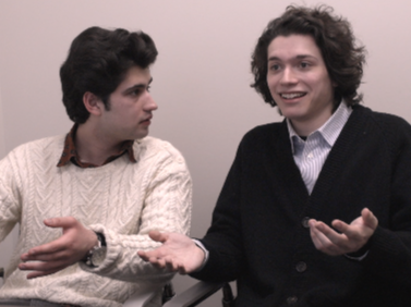 Two young men having a conversation in an indoor setting.