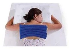 A woman lying on her side in bed with a blue heating or cooling pad on her back.