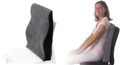 A woman sitting comfortably with her back against a back-support device that looks like a rock or stone.