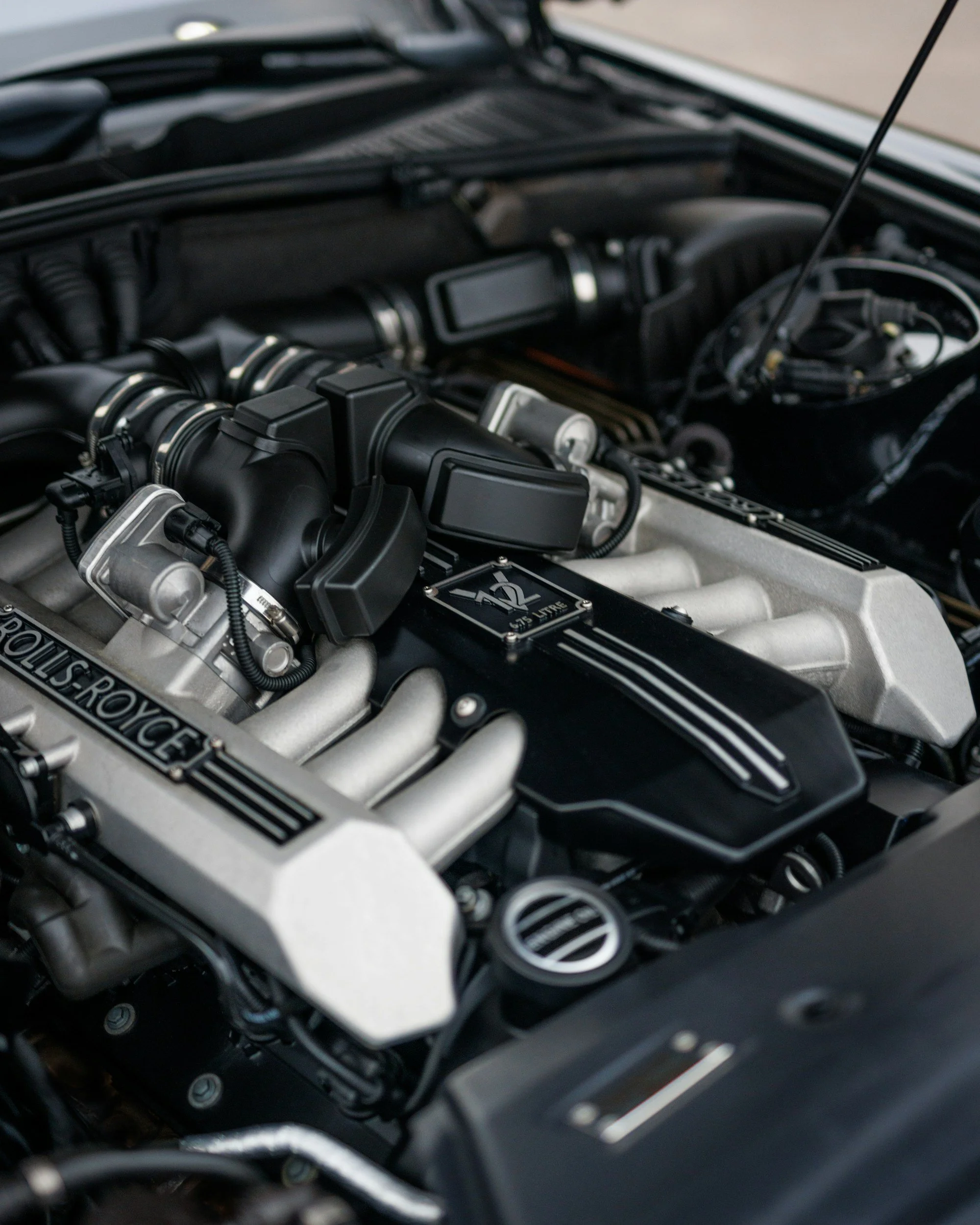 Close-up of a clean, black and silver Rolls-Royce engine in a car engine bay.