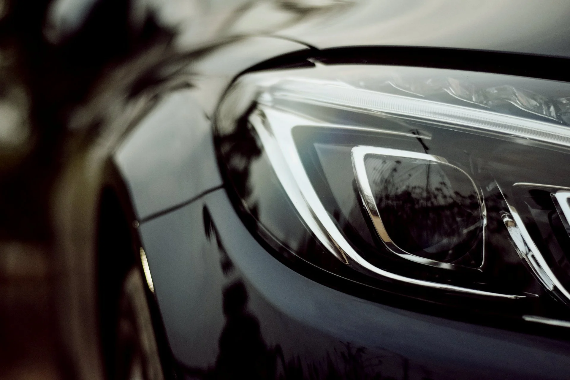 Close-up of a black car's headlight showing sleek design and reflective surfaces.