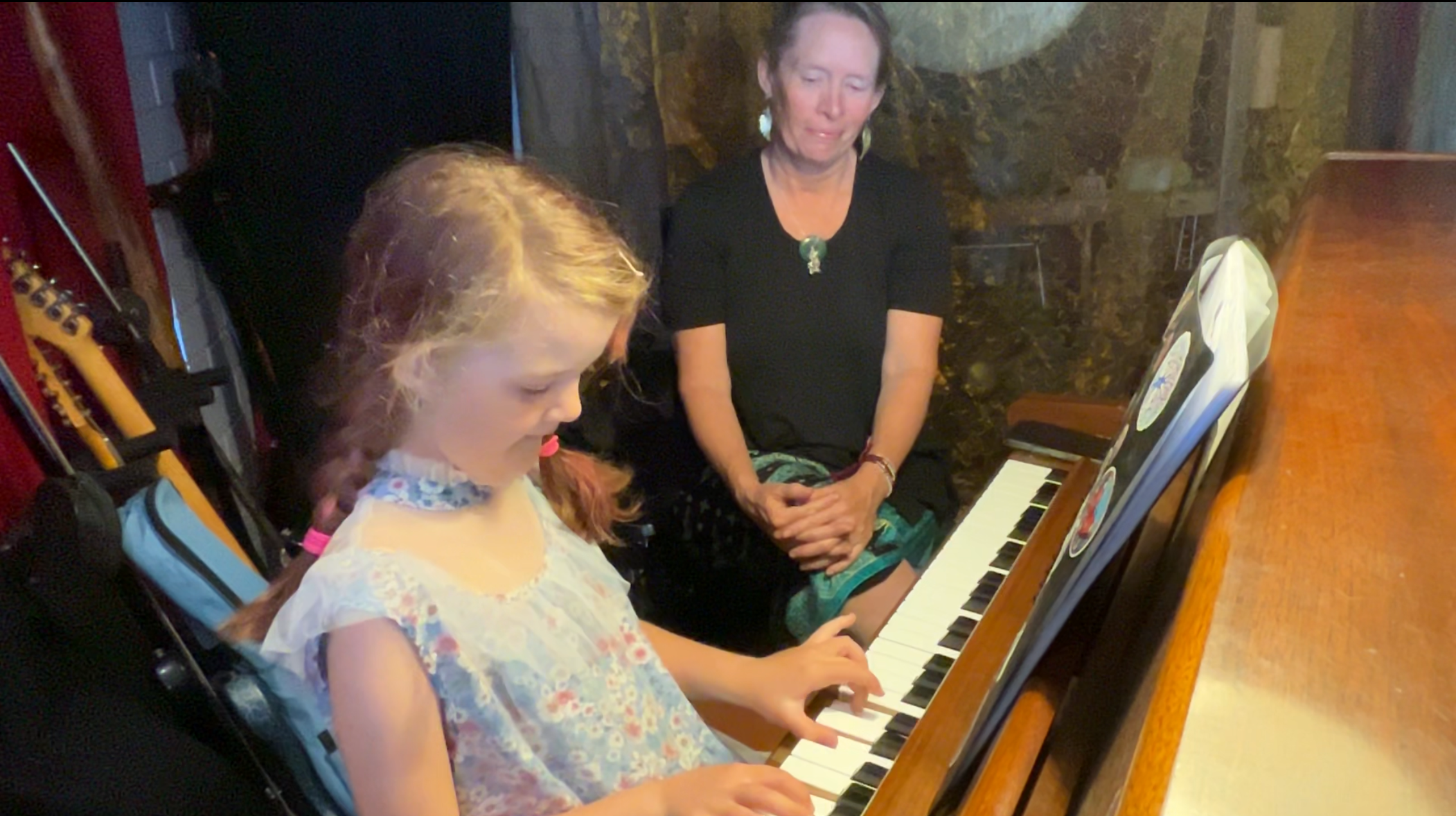 Tara teaching a young girl piano student with a piano.