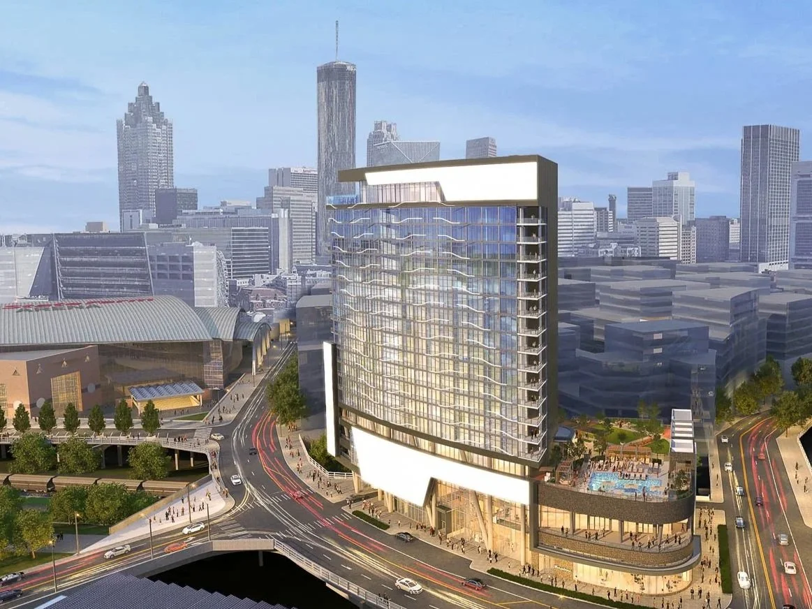 A modern high-rise building in an urban cityscape with a busy street intersection in the foreground and multiple skyscrapers in the background.