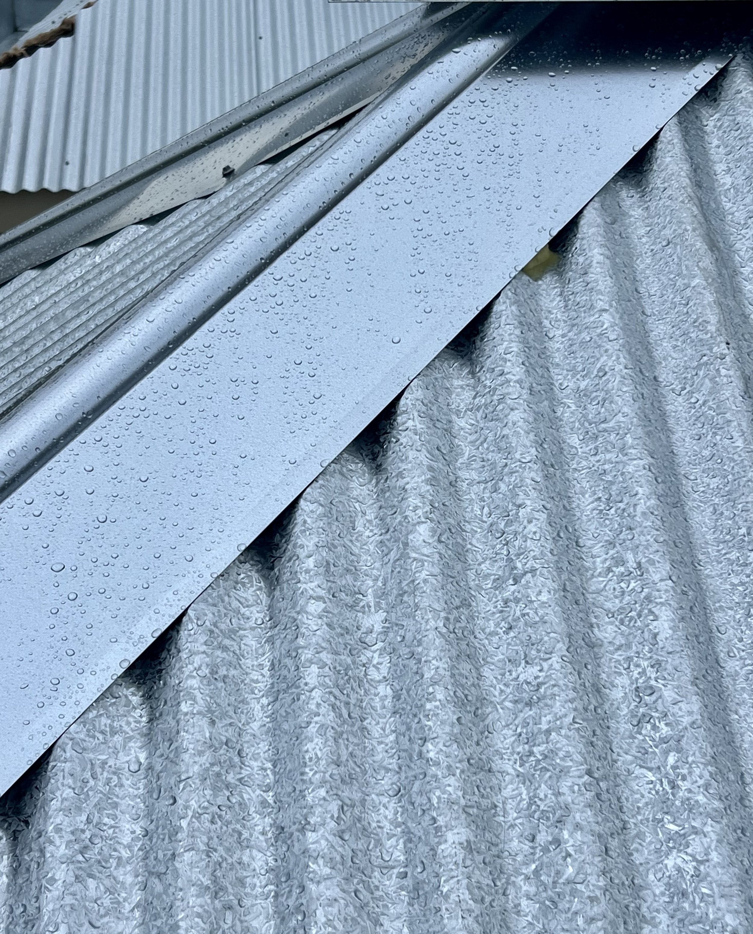 Close-up of metal roofing with water droplets on the surface.
