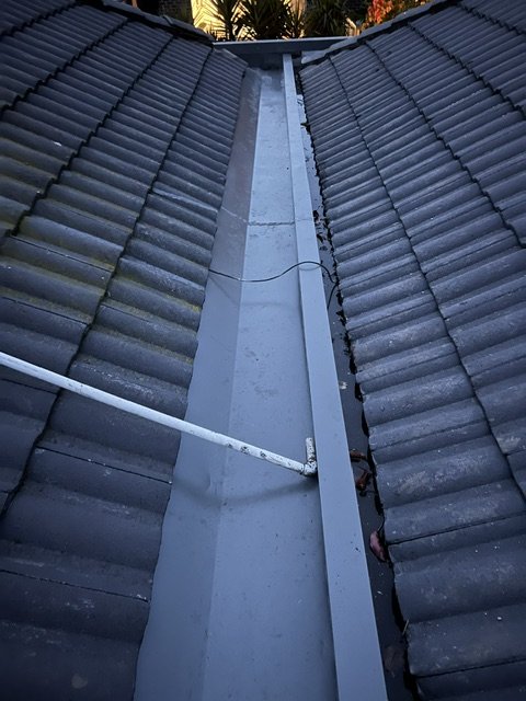 View of a roof valley with tiles on each side and a metal flashing in the center.