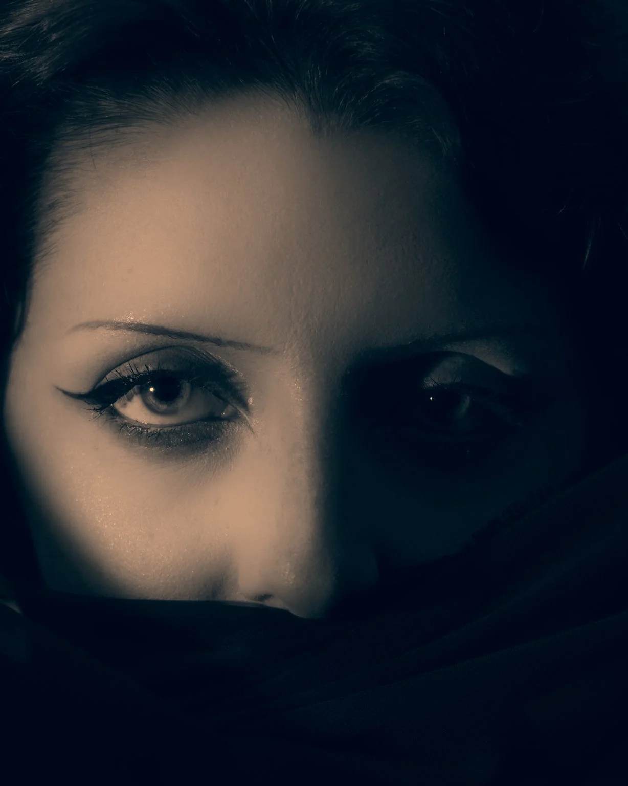 Close-up of a woman's face with a focus on her partly visible eyes and forehead, in black and white.