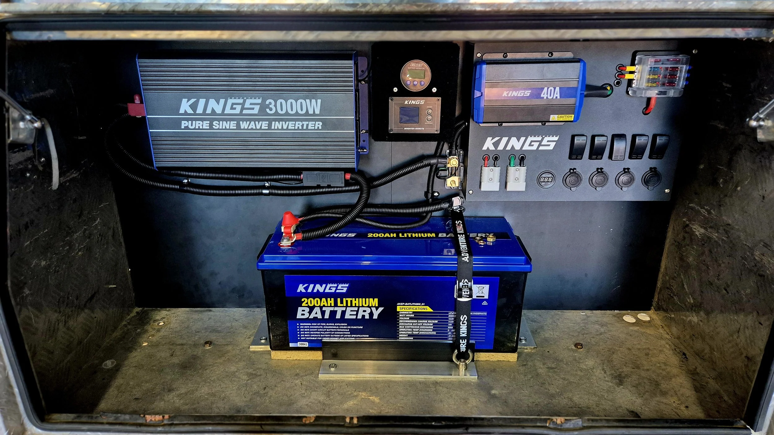 Inside a metal enclosure with electrical components including a 3000W inverter, 40A controller, a lithium-ion battery, and various switches and wires.