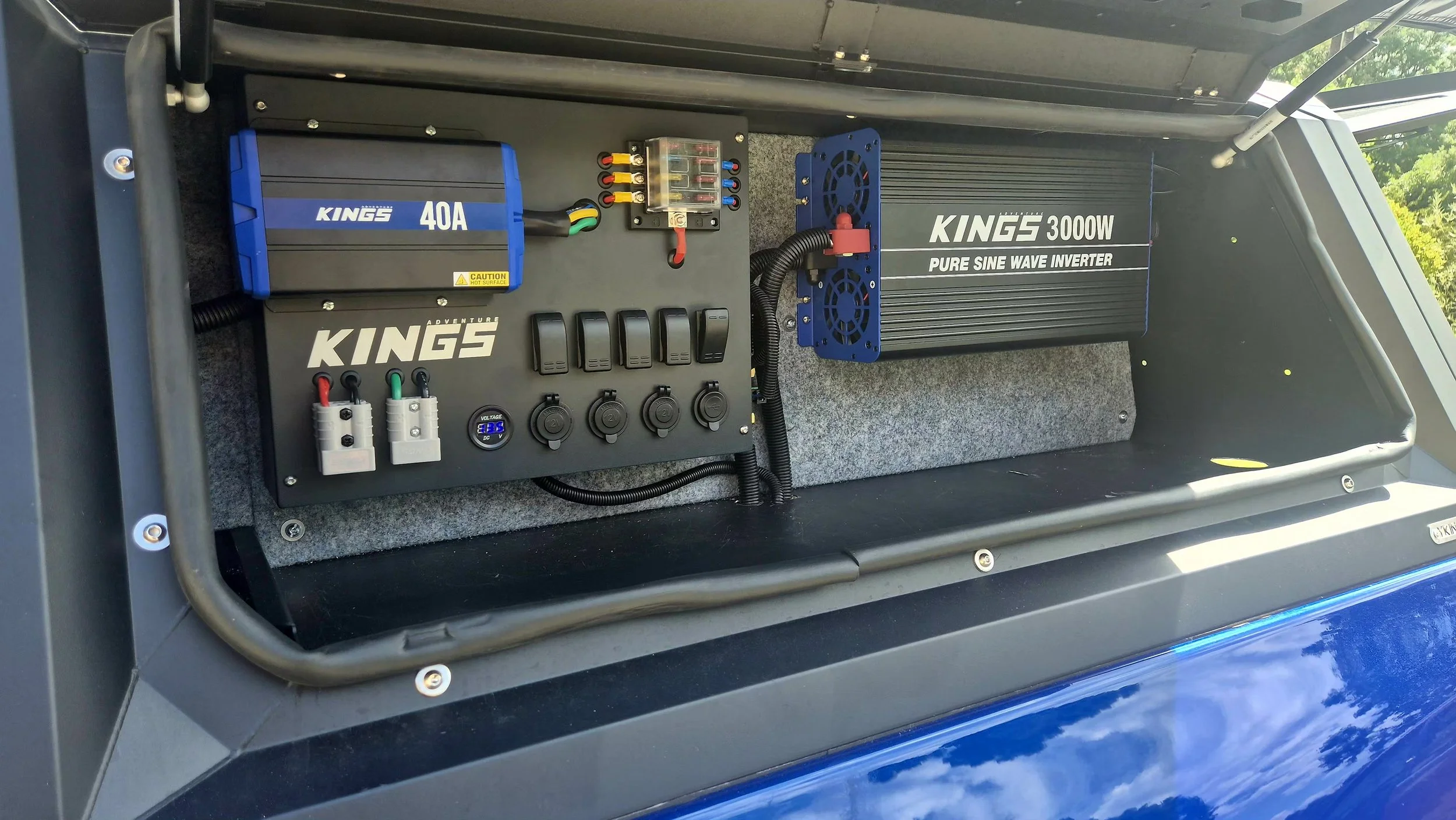 Electrical control panel with various switches, circuit breakers, a voltmeter, and a large inverter labeled 'KING'S 3000W PURE SINE WAVE INVERTER' inside a vehicle or equipment enclosure.