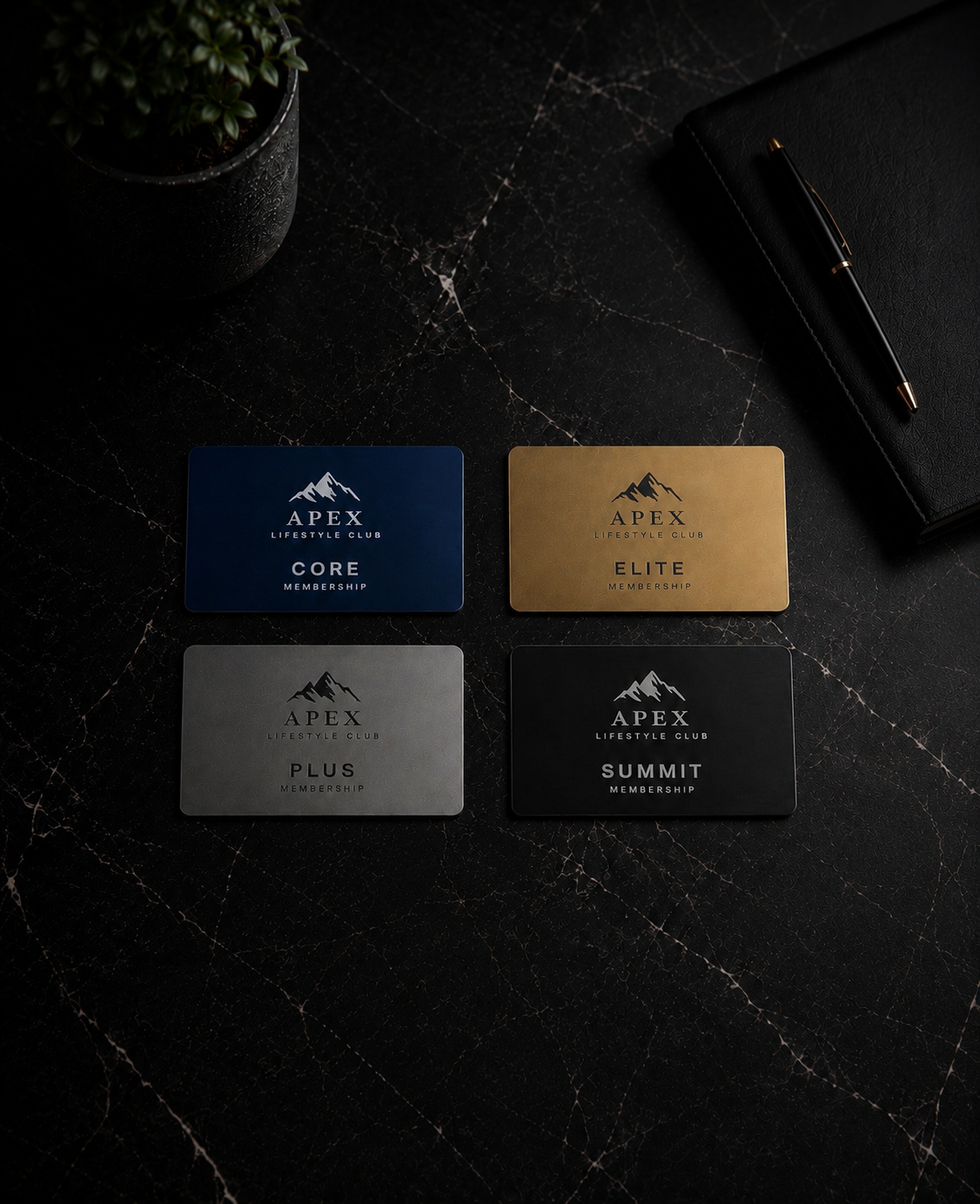 Four membership cards in blue, gold, gray, and black with the Apex Lifestyle Club logo and different membership levels: Core, Elite, Plus, and Summit on a dark marble surface, with a black leather notebook, a black pen, and a potted plant nearby.