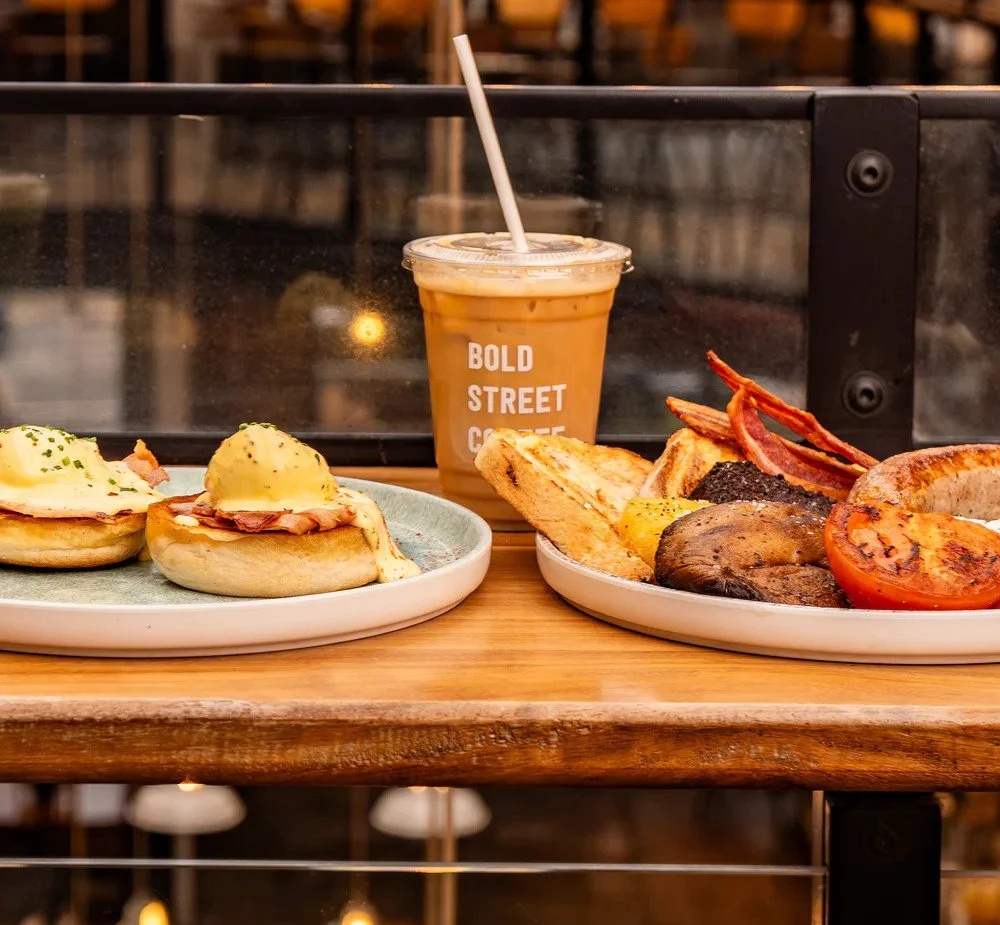 A breakfast meal with two plates of food, a coffee, and toast in a casual dining setting.