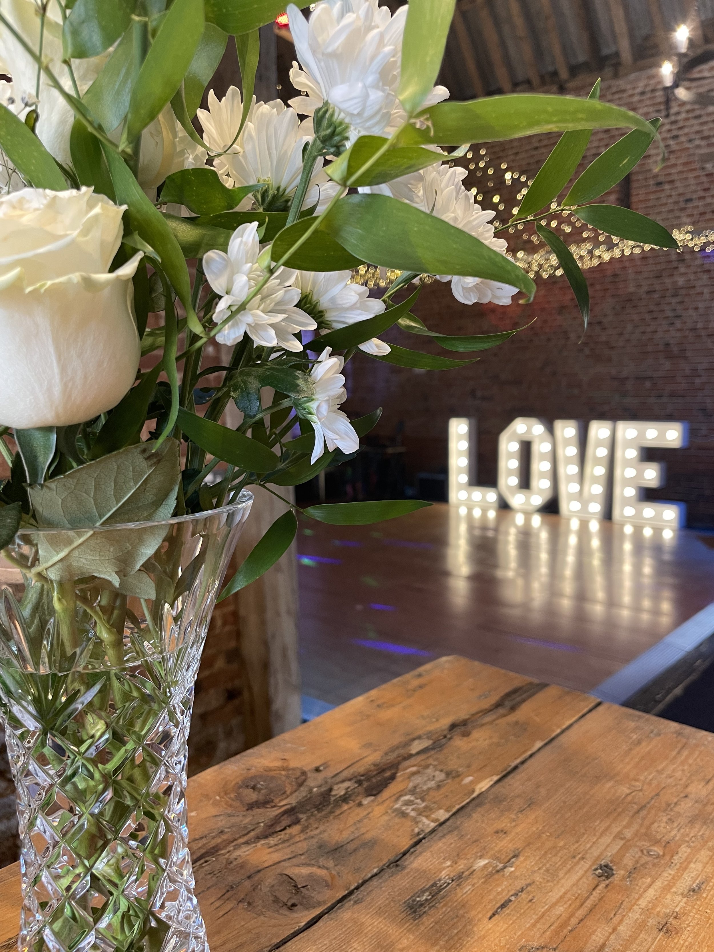 Giant love letters showing in the background on the dancfloor at Glebe Farm Barn wedding venue Norfolk