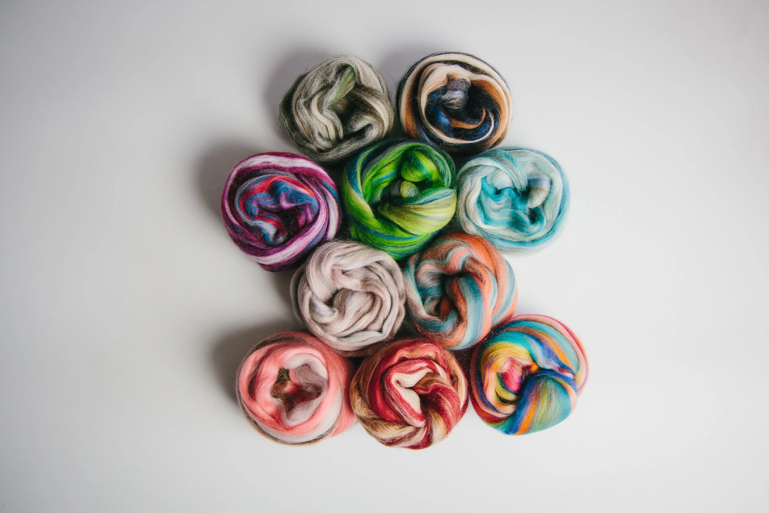 Multiple colorful balls of yarn arranged in a circle on a white surface weaving Oxford - Product Photography Oxfordshire