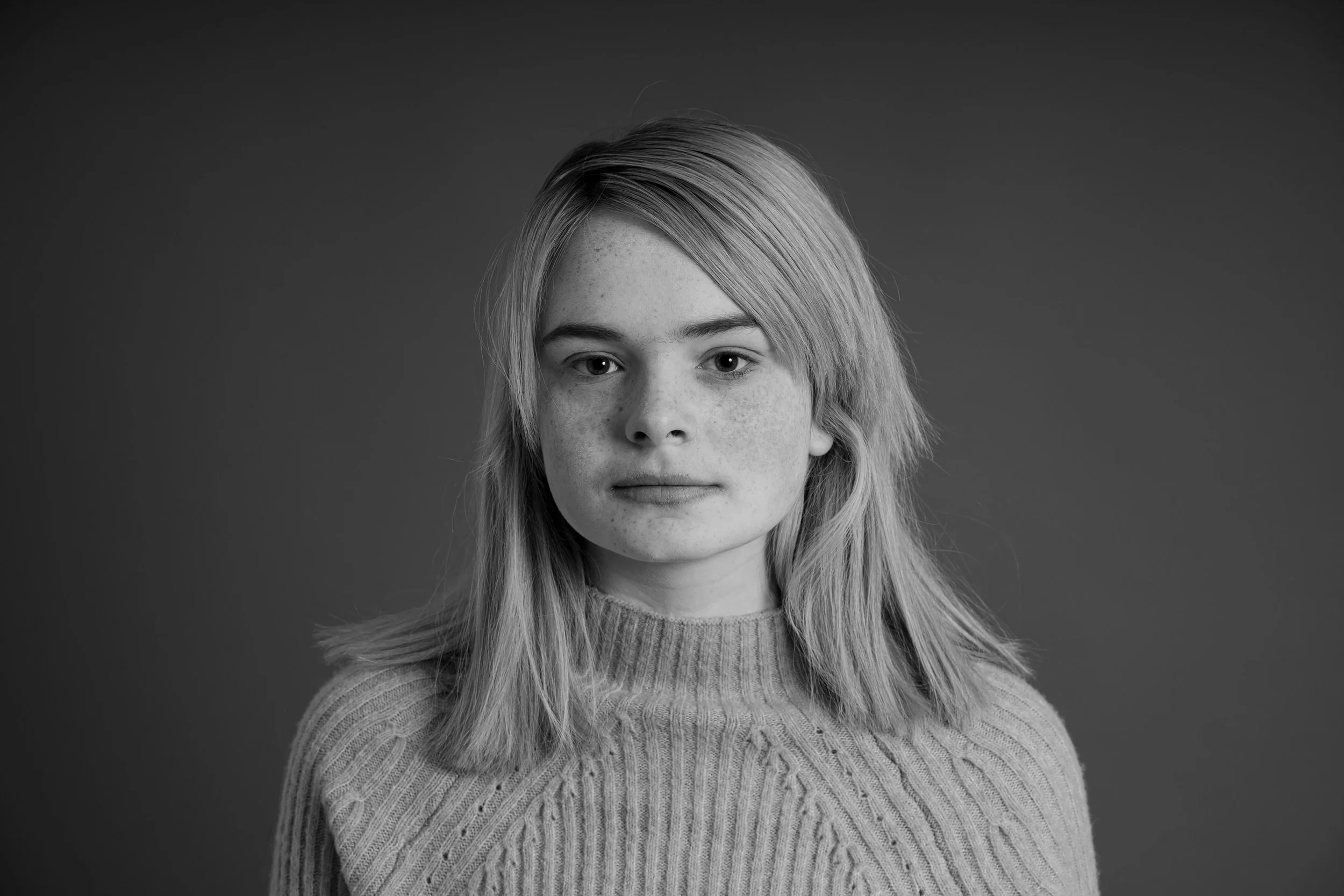Black and white portrait of a young woman with shoulder-length hair wearing a knitted sweater.