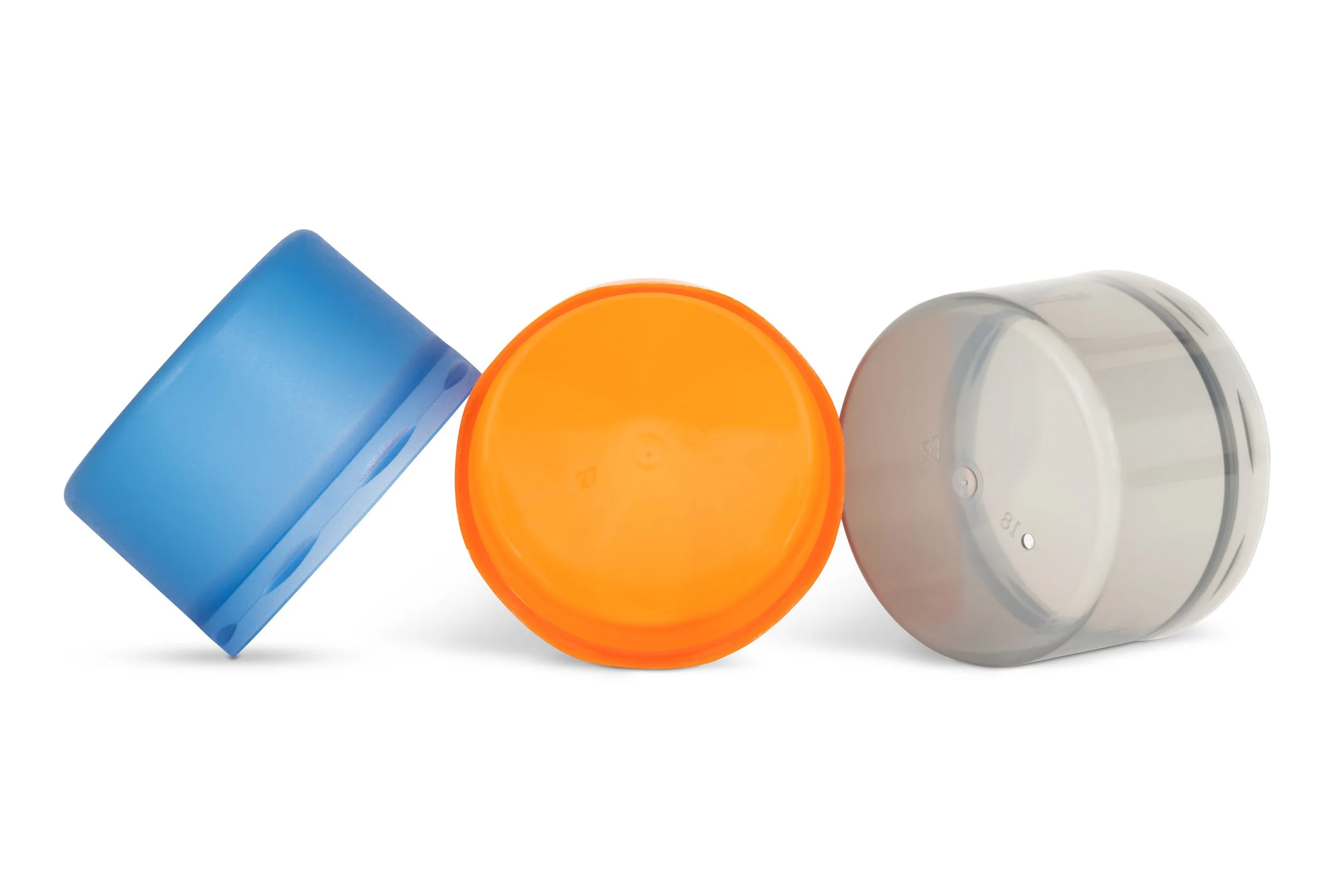 Three prescription pill bottles with blue, orange, and white caps, lying on a white surface.
