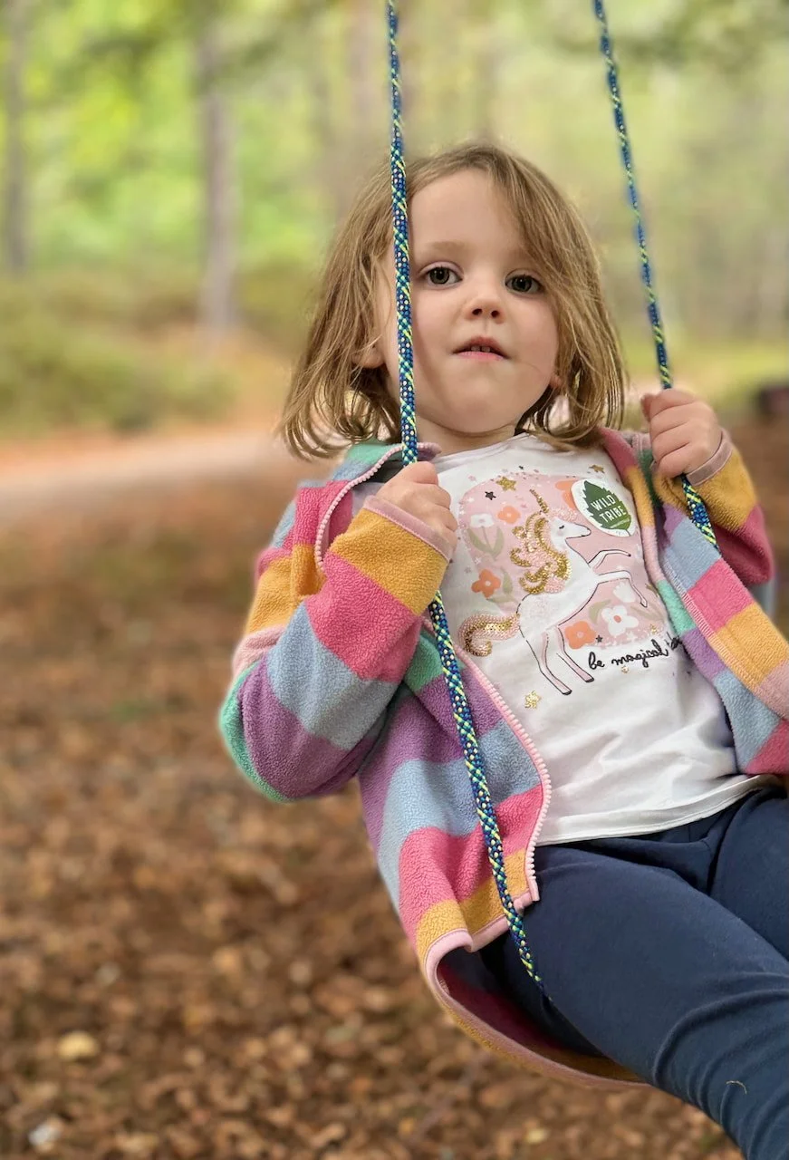girl on homemade swing in beach woodland
