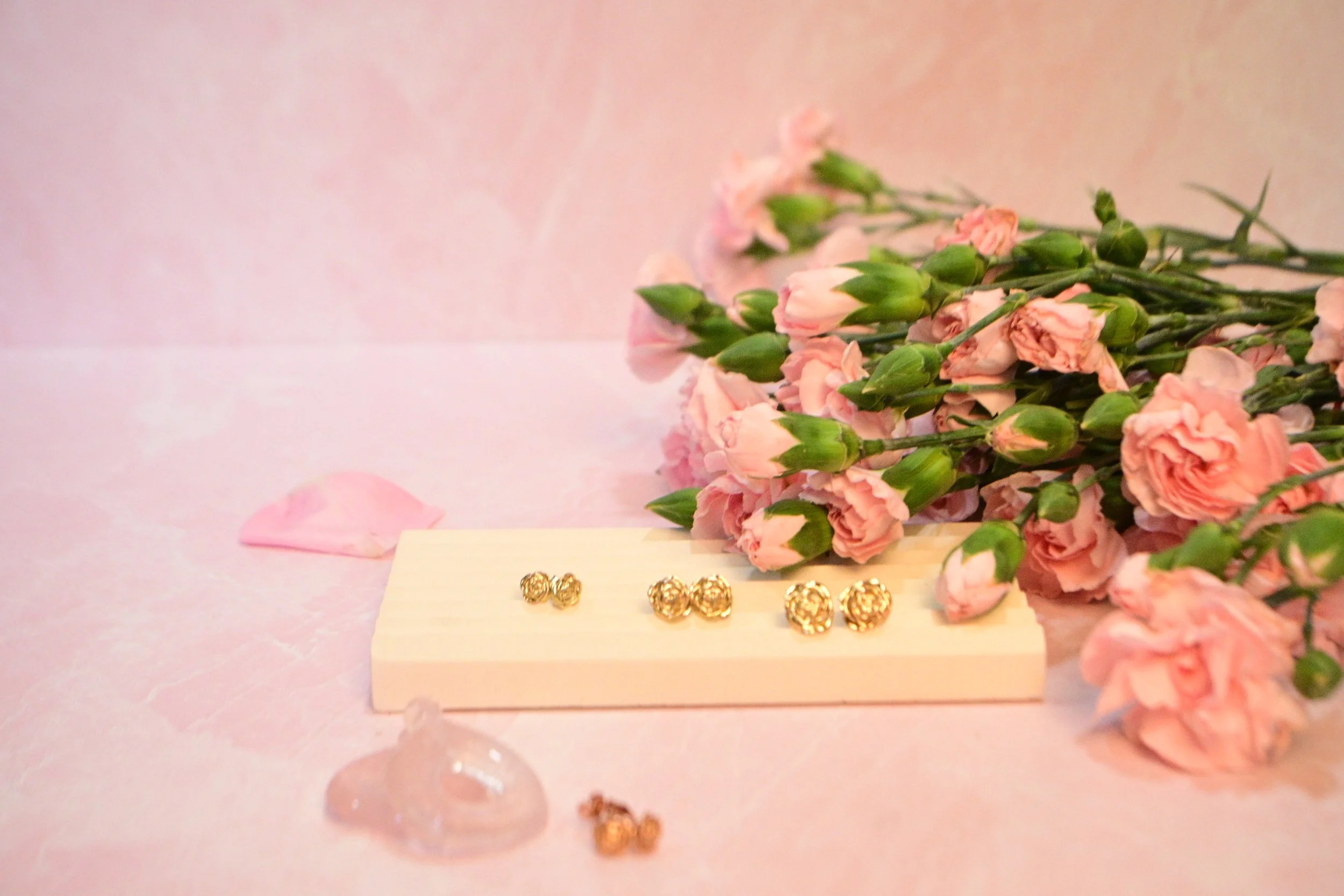 Pink flowers, pink rose quartz background, featuring rose gold flower earrings.