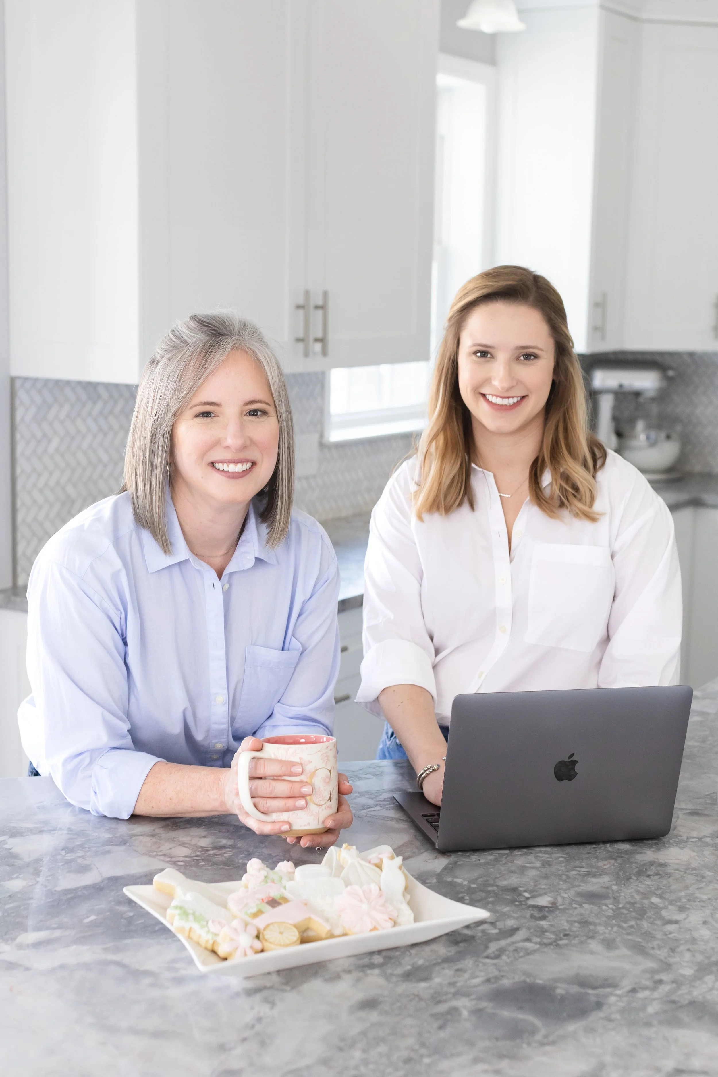 Smiling woman in a modern kitchen working on a computer.