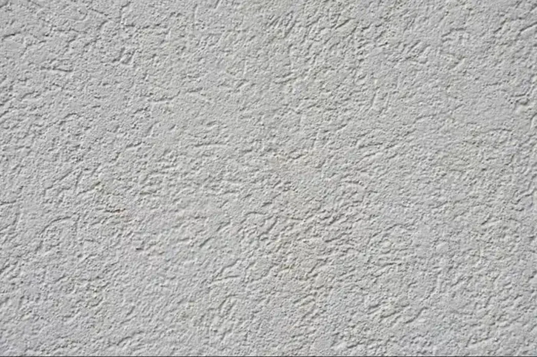 Close-up of a textured white wall with rough stucco finish.