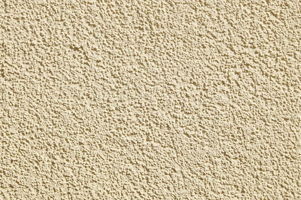 Close-up of a beige, textured, stucco wall surface.