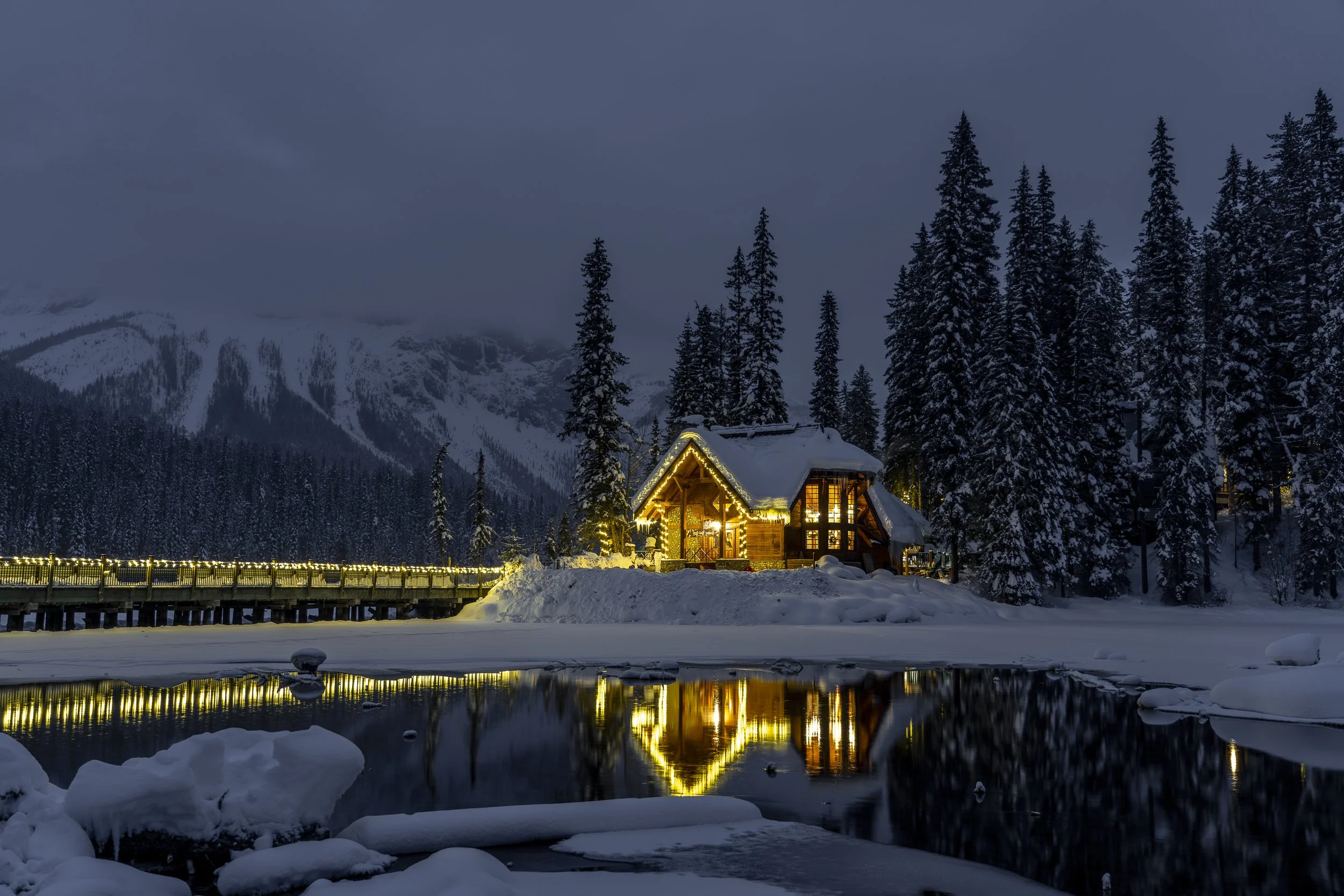 Cilantro on the Lake at Emerald Lake Lodge reflected in a partially frozen Emerald Lake early morning, with snowy trees and mountains behind.