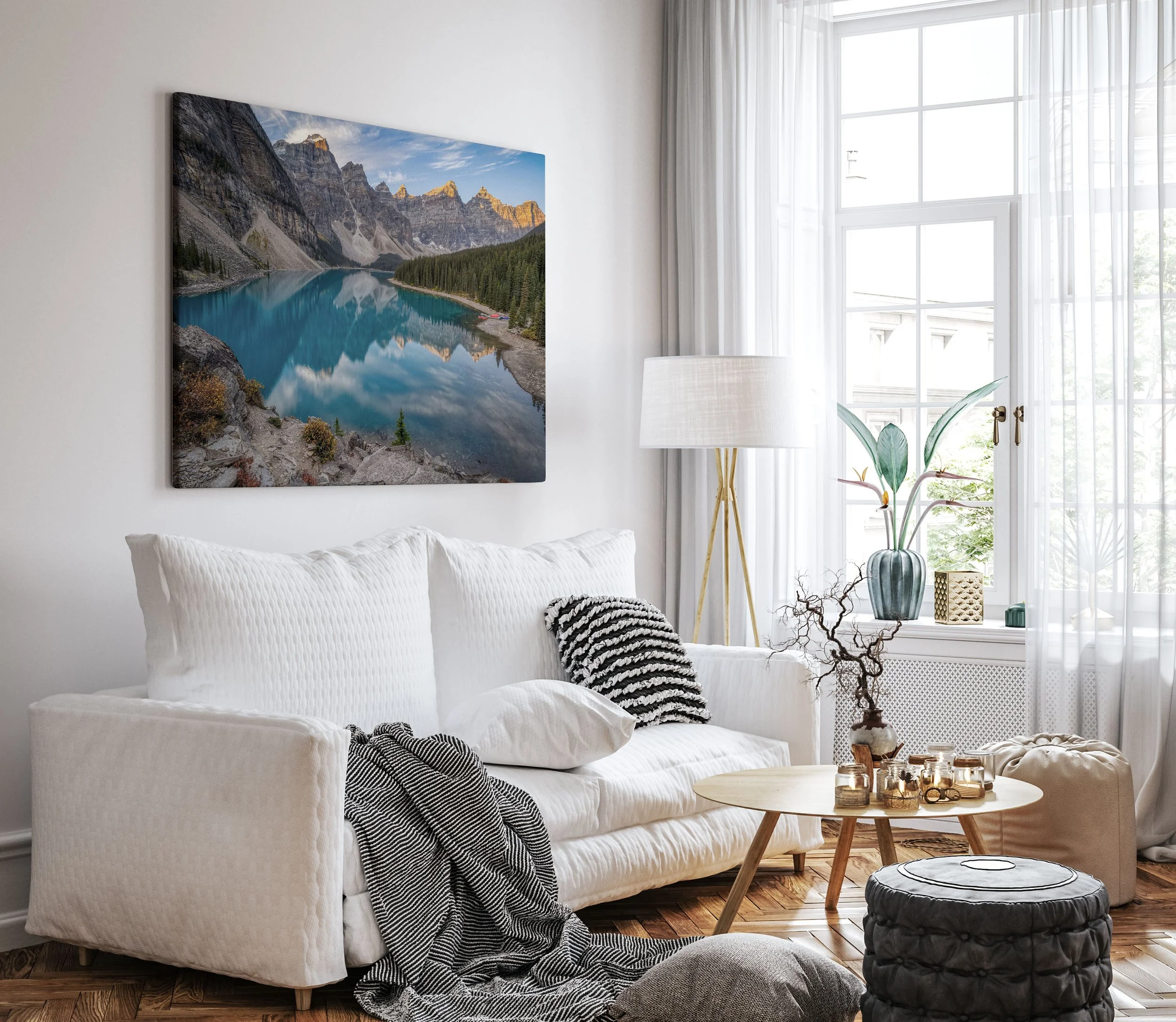 Oversized Moraine Lake Sunrise canvas print displayed frameless on a white wall above a white linen sofa in a bright Scandinavian-style living room with hardwood floors and sheer curtains.