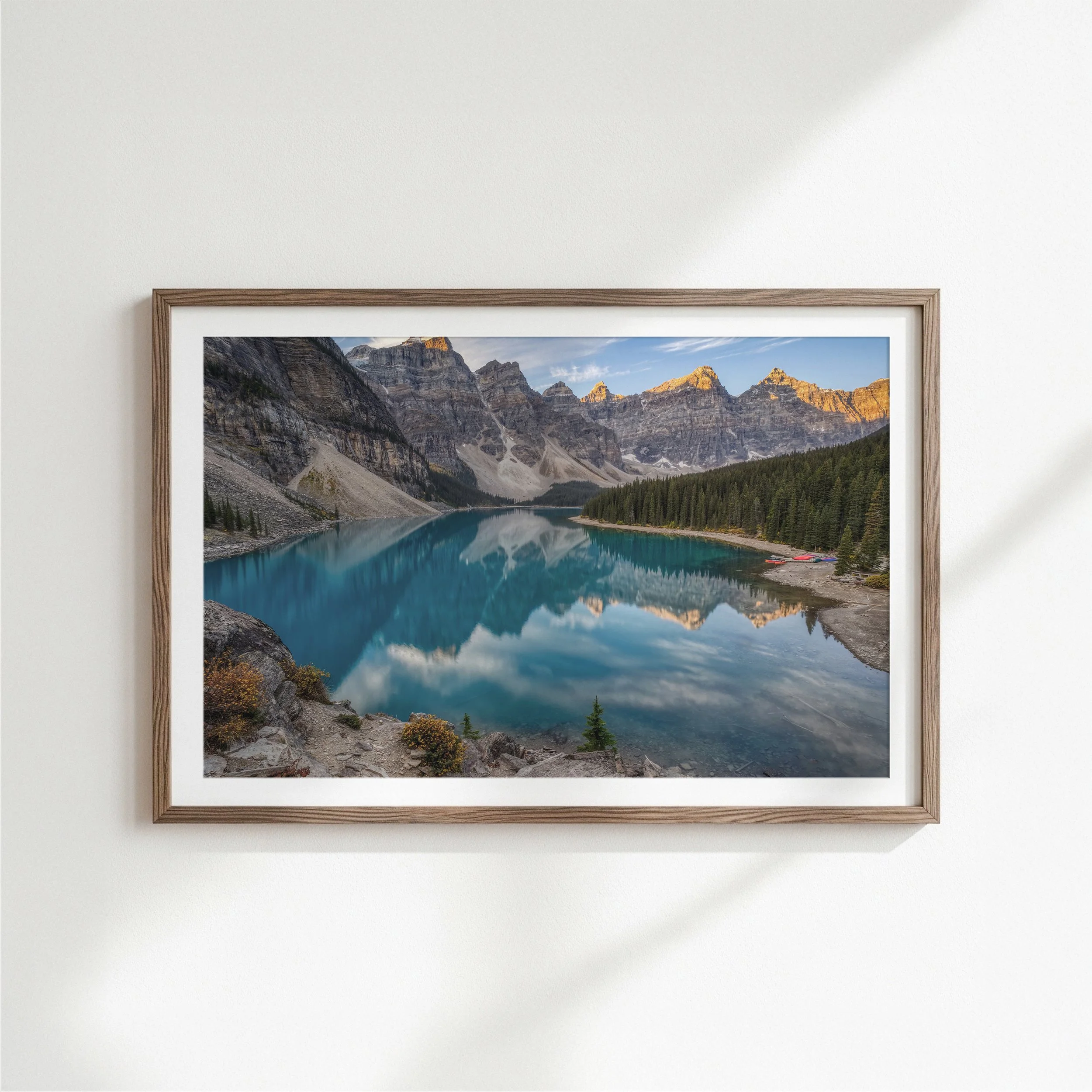 Moraine Lake Sunrise fine art print in a slim dark espresso wood frame with white mat, displayed on a clean white wall with soft natural side lighting.