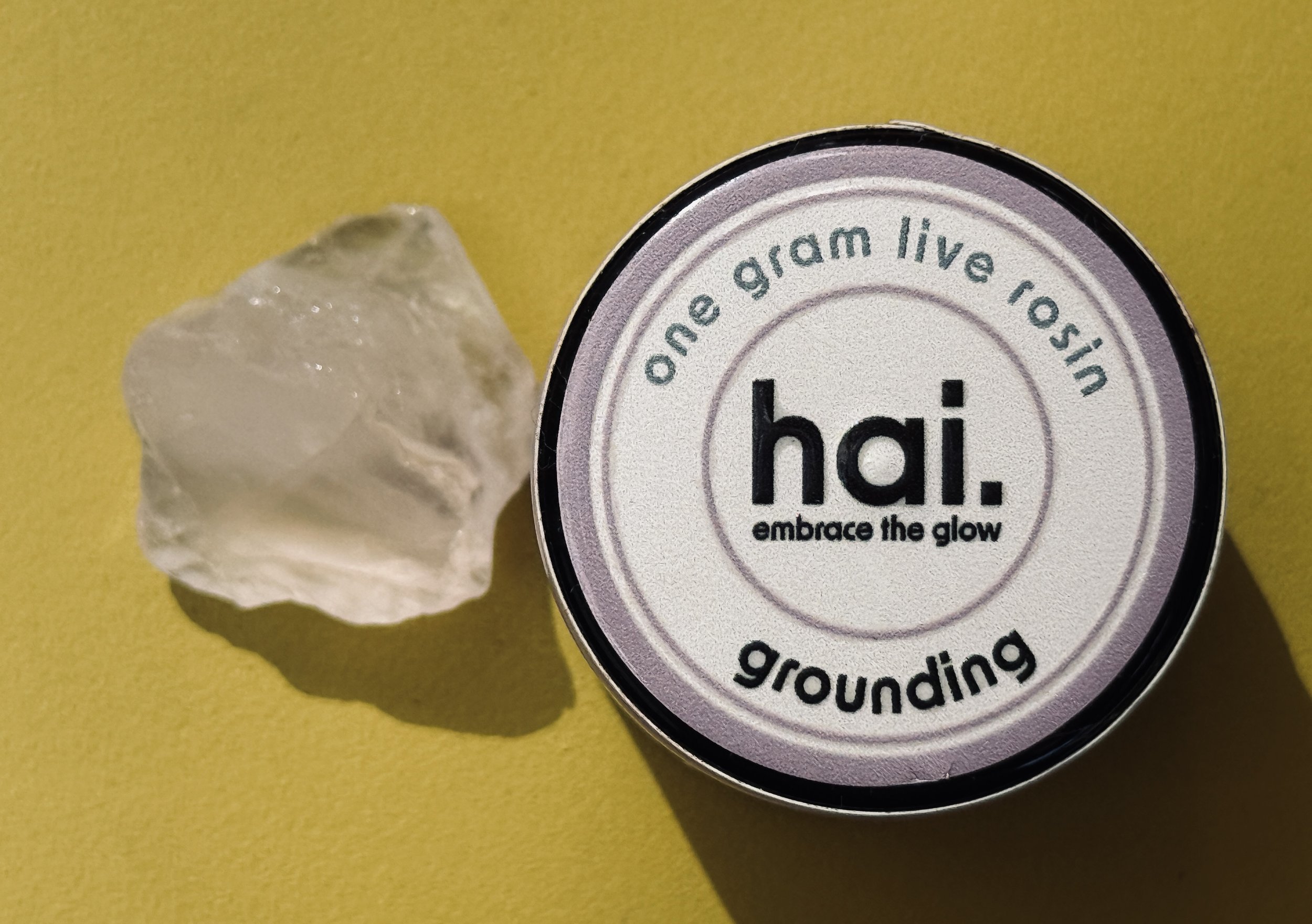 hai cannabis one gram live rosin jar in grounding/purple with a rose quartz stone next to it
