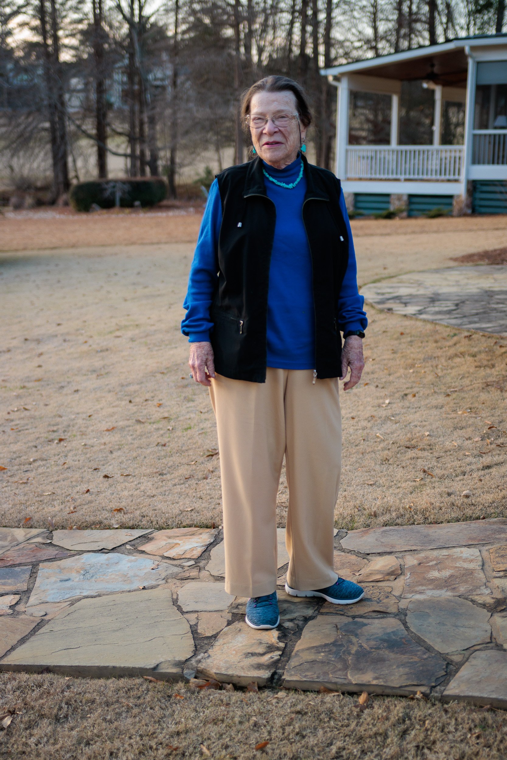 Person in a blue shirt and black vest standing on a stone path