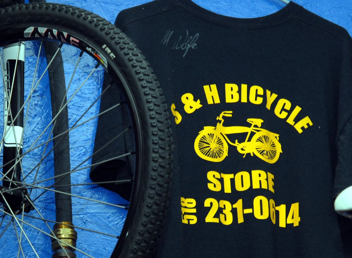 S&H Bicycles' t-shirt hangs on shop wall.