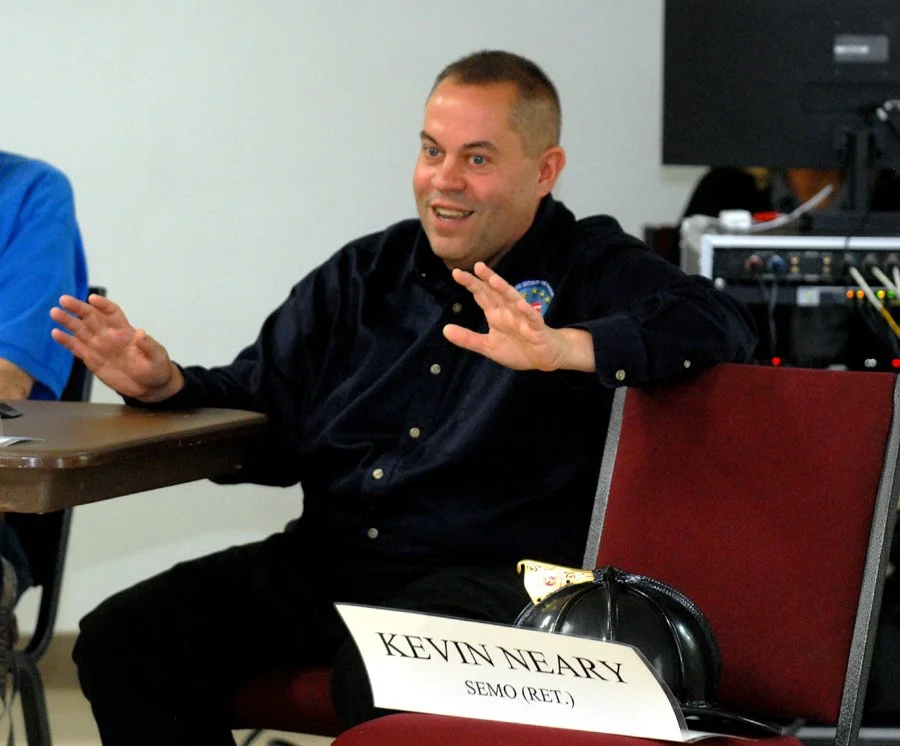 9/11 rescue worker Brian Head gestures in front of a placard for his then-boss, the lare Kevin Neary.