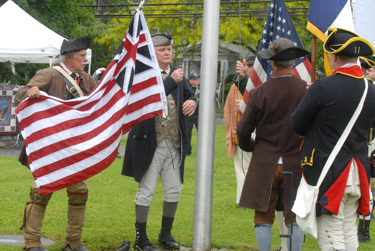 Men in historic outfits, raising the flag in a small town in Schoharie County