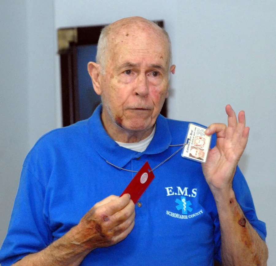 Cobleskill Rescue Squad volunteer John Copland holds up his IDs from 9/11.