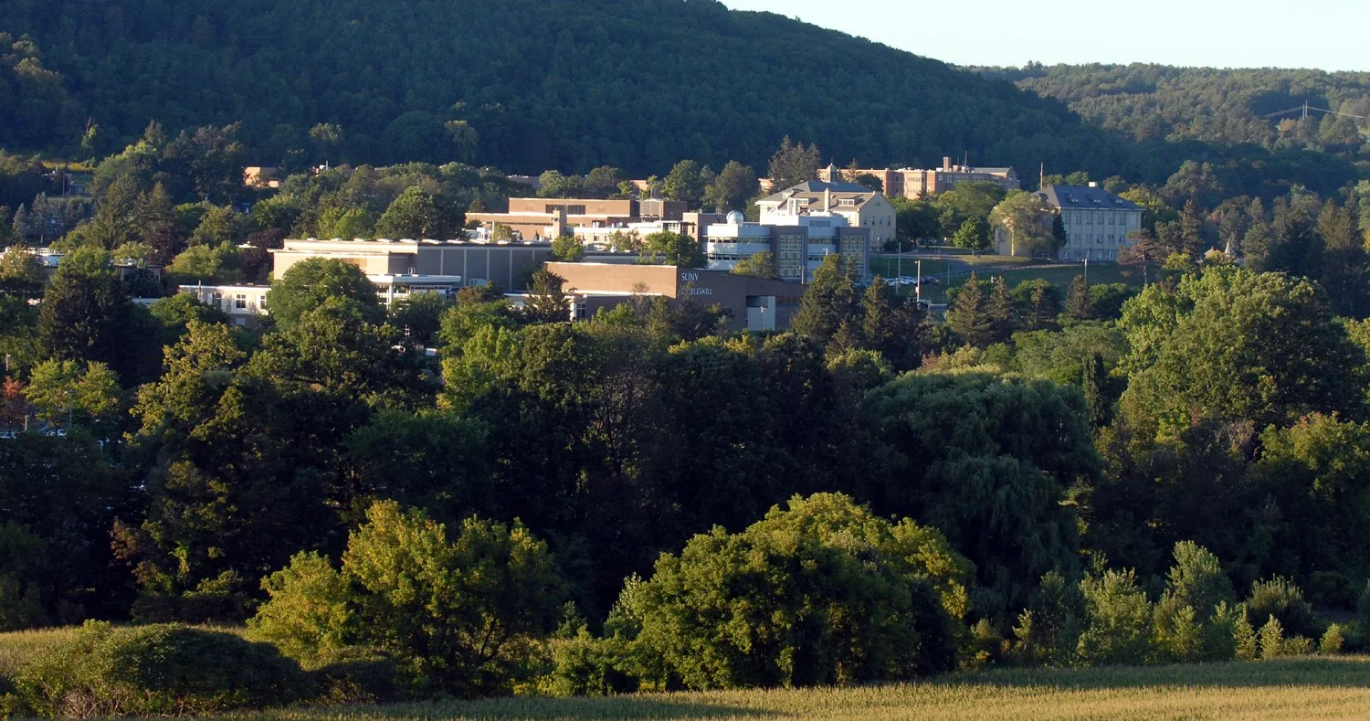 Landscape view of Cobelskill SUNY Campus with trees, meadow and campus buildings