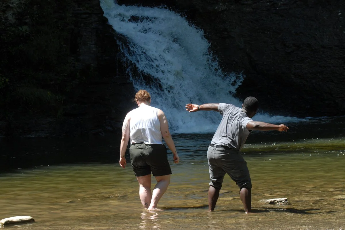 A couple skips rocks in the plunge pool below Mine Kill Falls.