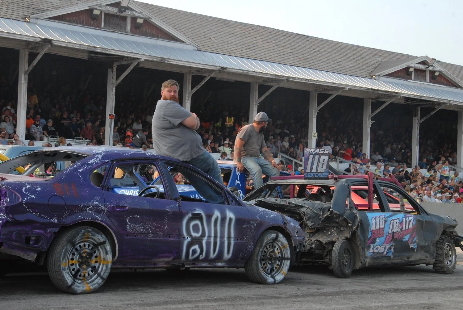 Men sit on top of Fair Demo Derby cars