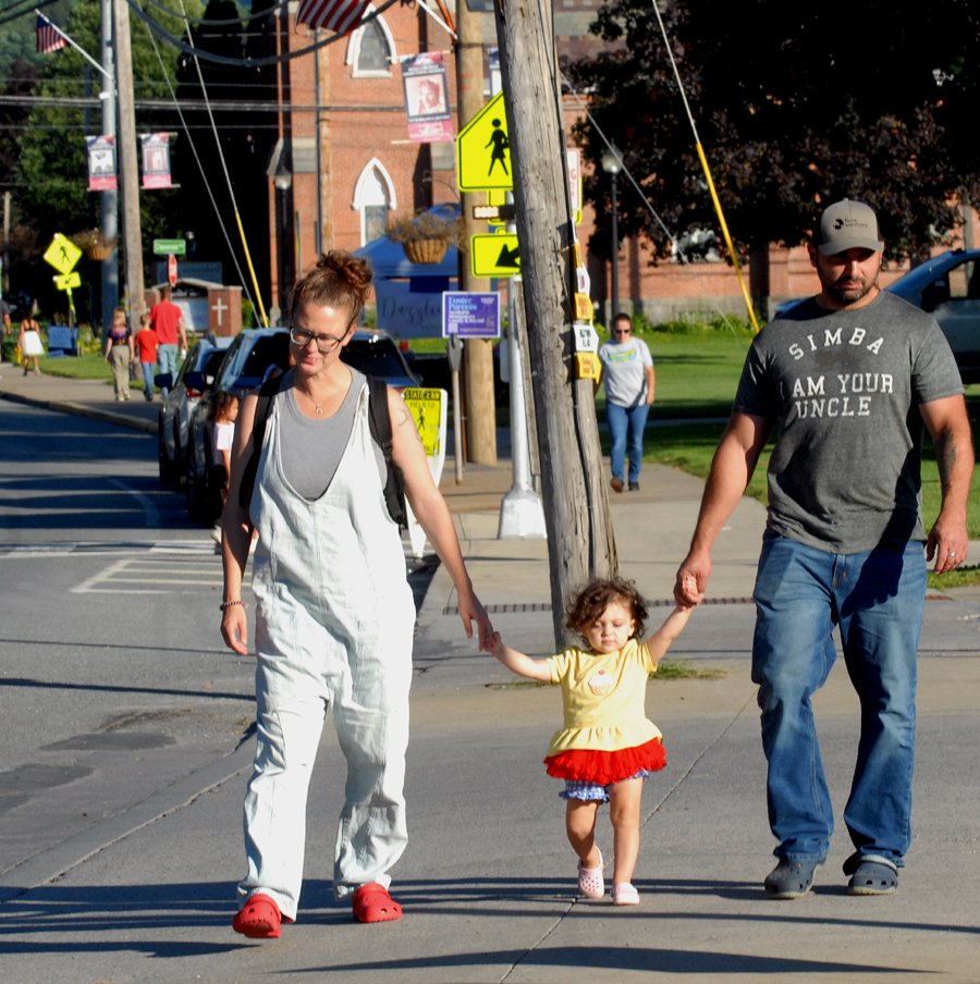 A young family walks down a Middleburgh sidewalk.
