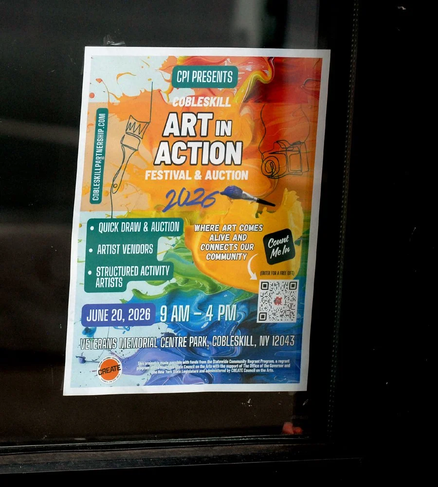 A poster advertises the Cobleskill Partnership's Art in Action Festiva.