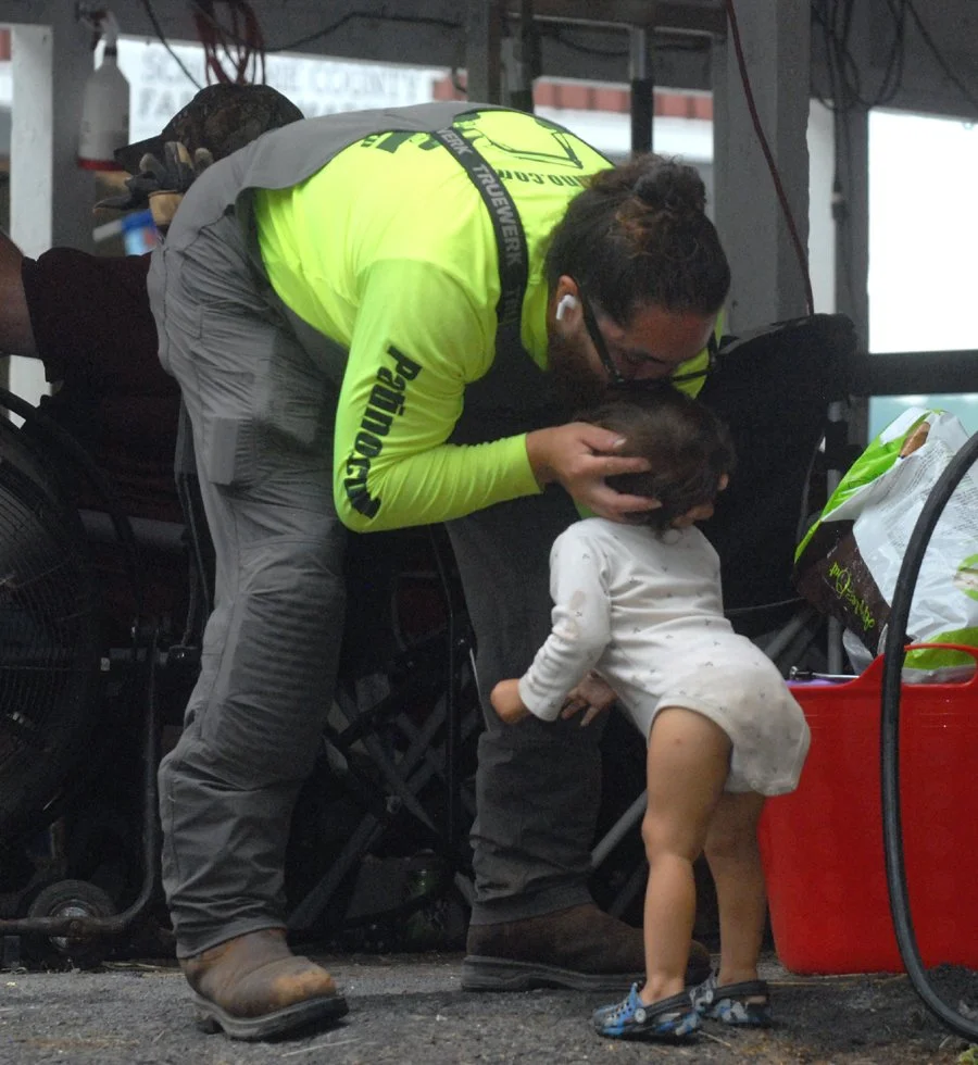 A dairy exhibitor kisses his daughter on the head.