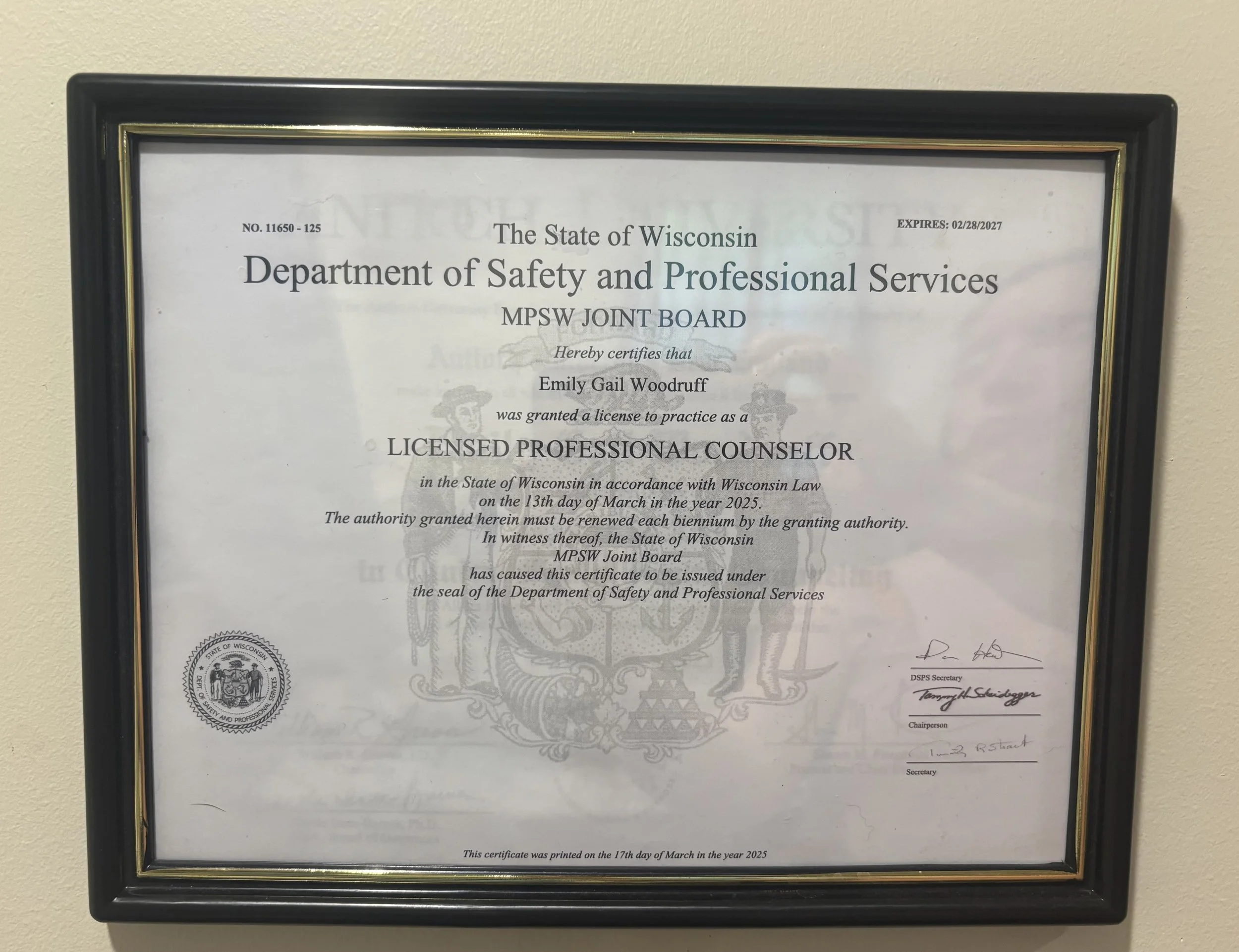 Framed Wisconsin Department of Safety and Professional Services license certificate for Emily Gail Woodruff, authorized to practice as a licensed professional counselor, with signatures at the bottom.