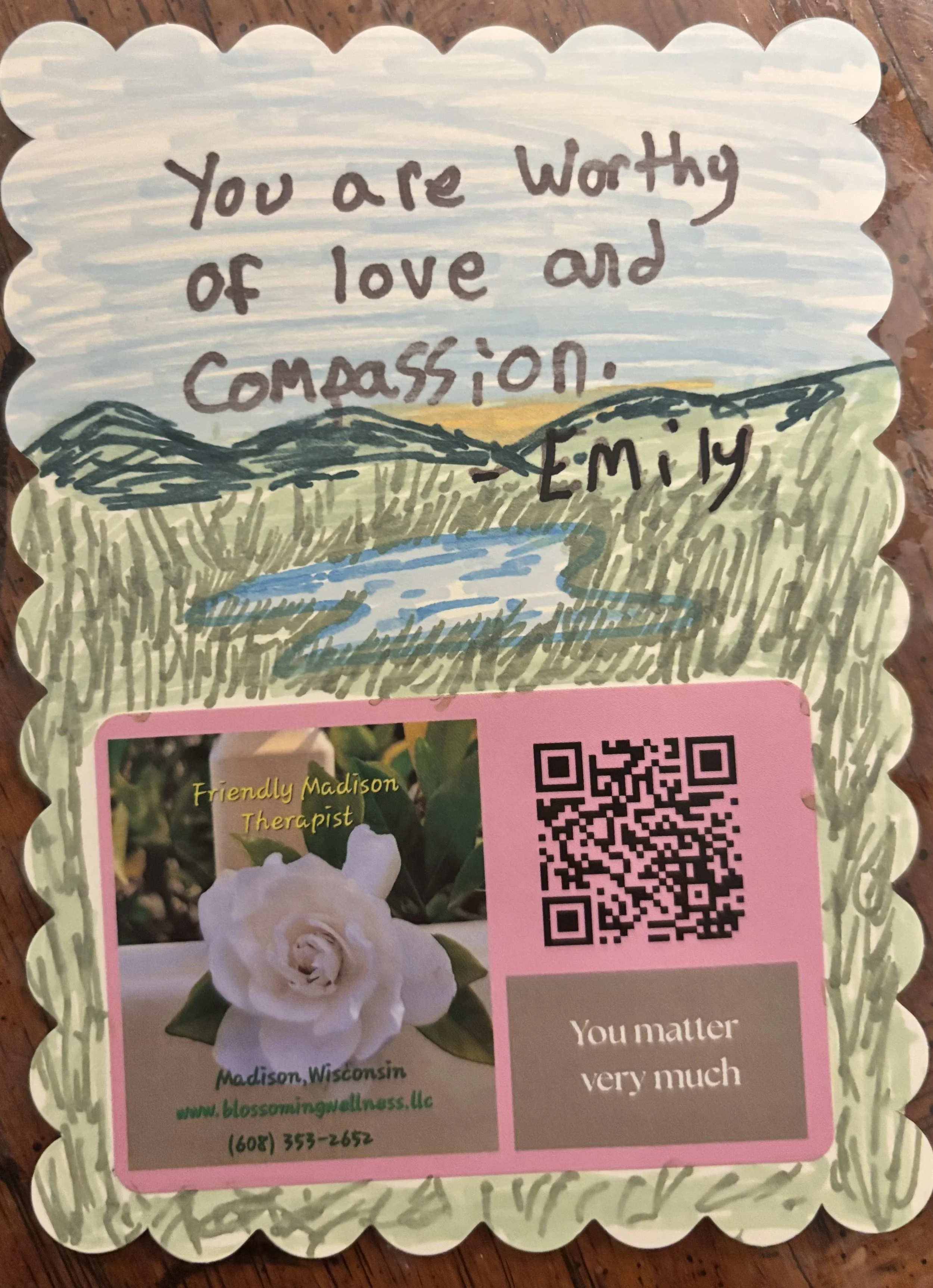 Handwritten note on decorative paper with landscape watercolor illustration, reading: "You are worthy of love and compassion."