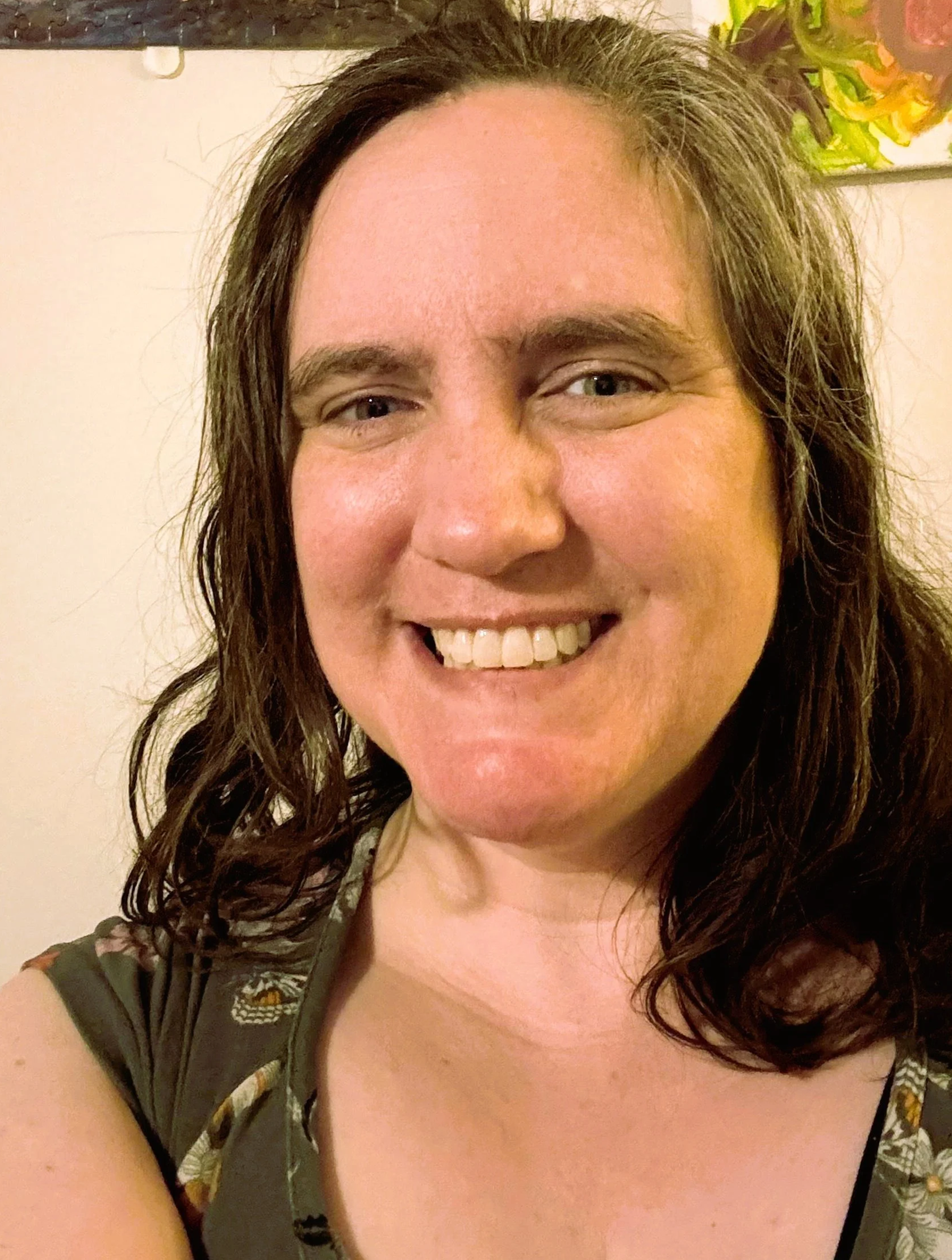 A smiling woman with long brown hair wearing a camouflage outfit.