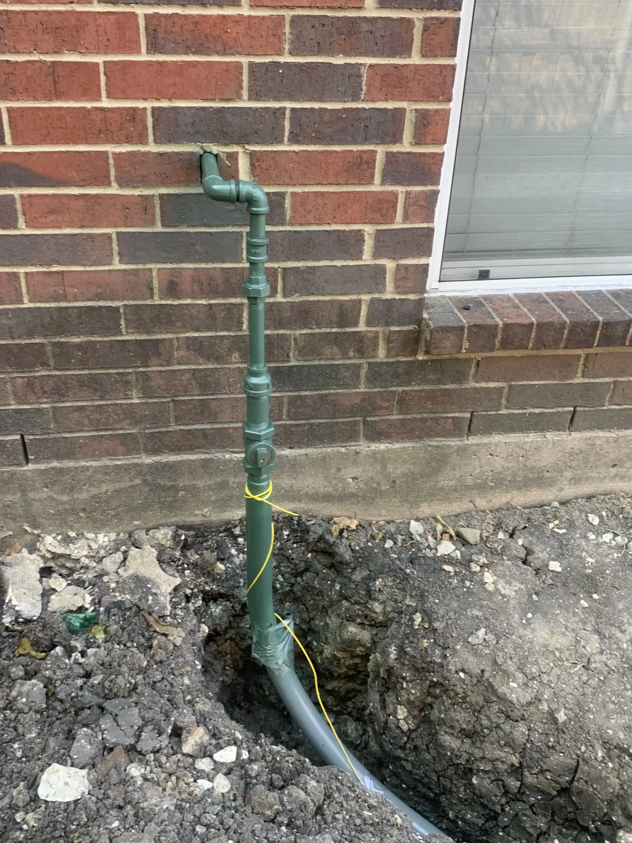 Gas riser pipe installation against brick home exterior