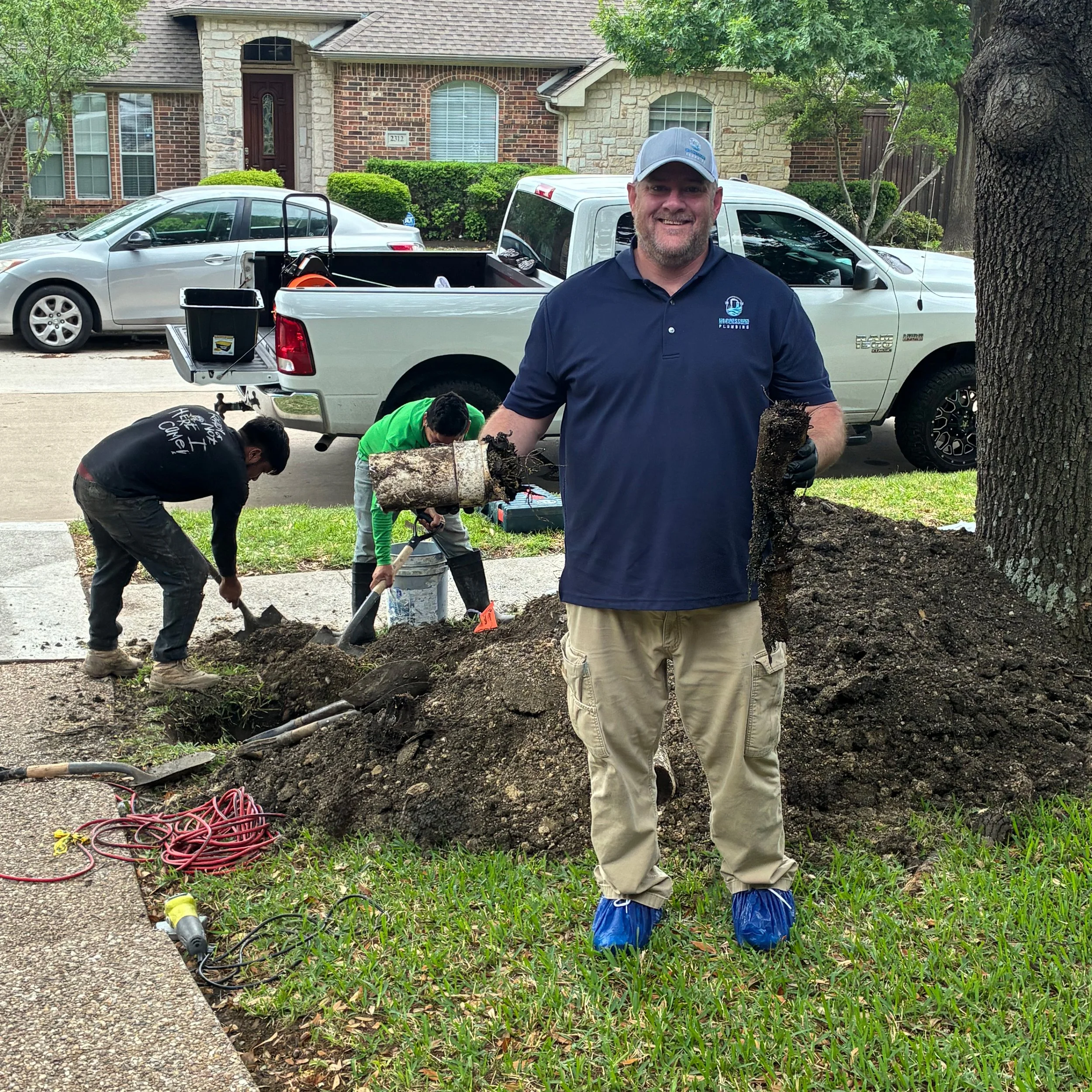 Nick Green of No Pressure Plumbing holding a section of sewer line cleared of heavy root intrusion on a residential service call in Collin County Lightbox: Sewer line cleared of root intrusion on a residential service call.