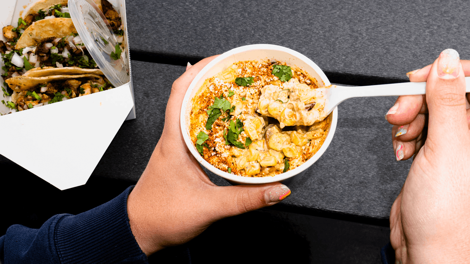 Person holding a bowl of creamy pasta with cilantro on top, and a spoonful of the pasta.