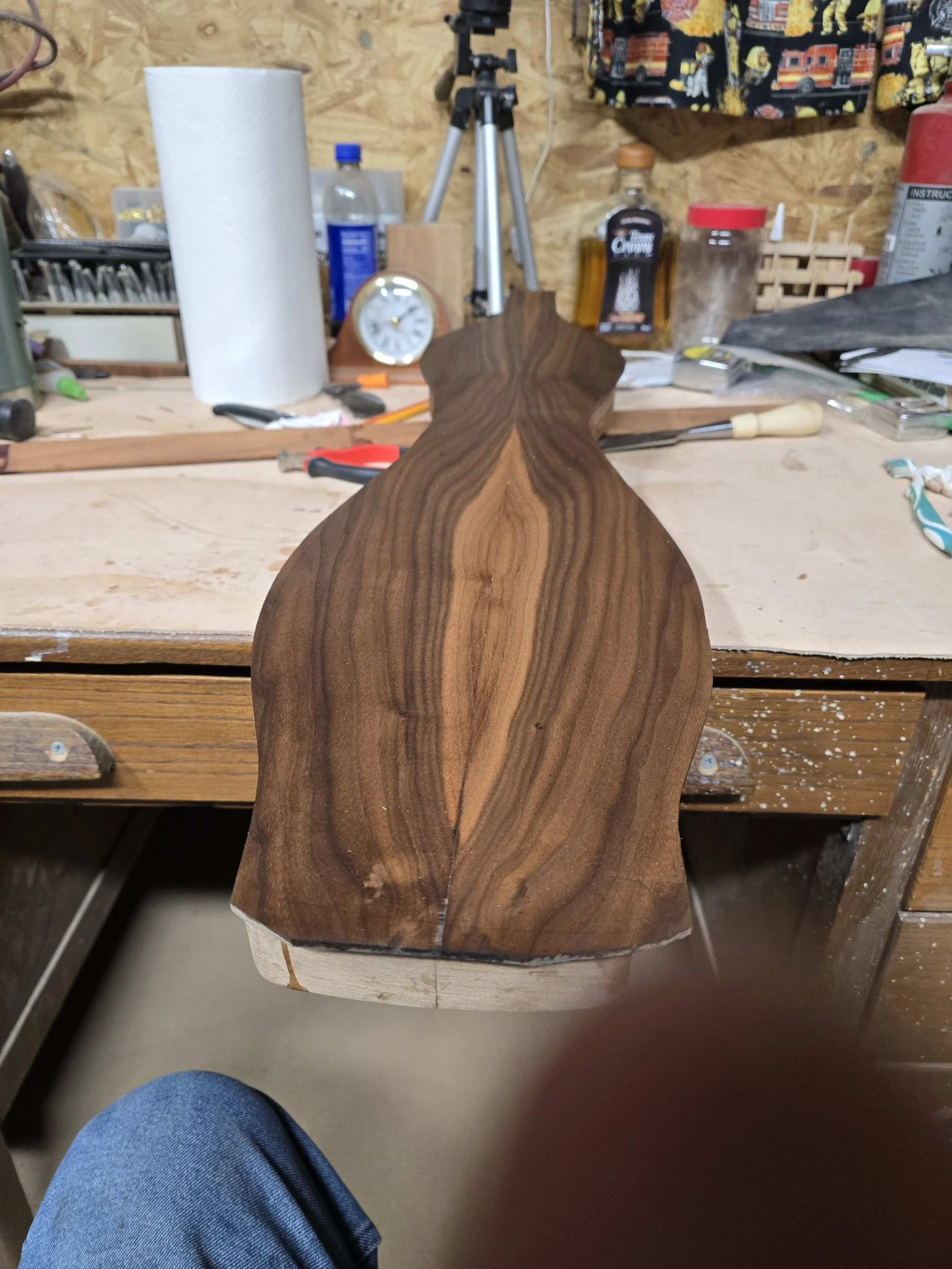 A partially carved wooden piece on a workbench in a woodworking shop.