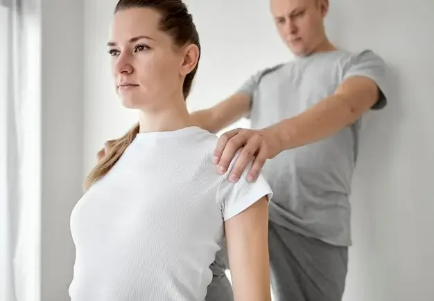 a physical therapist providing manual treatment to a patient's shoulder area.