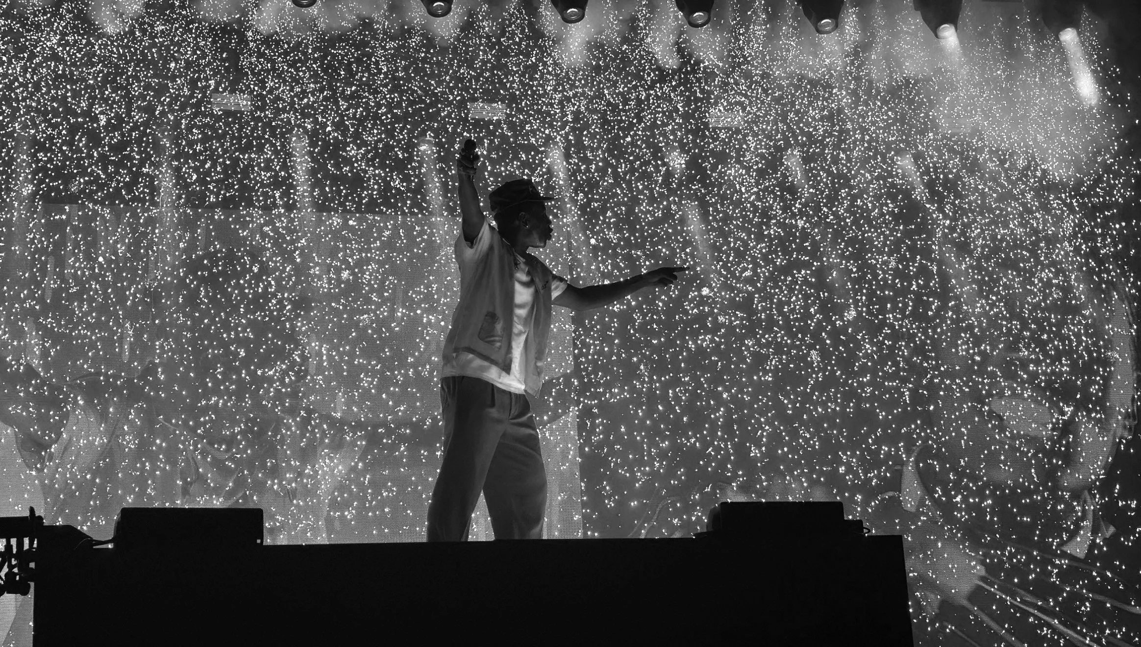 A person on stage dancing in front of a backdrop filled with numerous tiny bright lights, creating a starry or glittering effect.