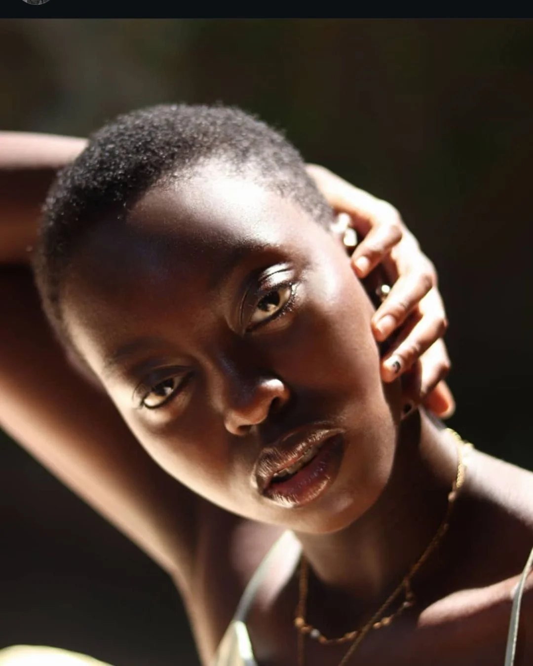 A black woman in a cave with light bouncing on the head.