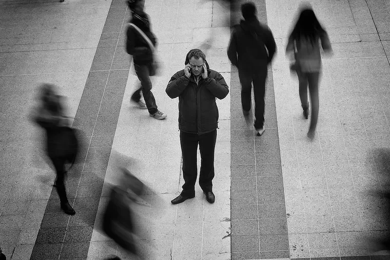 A gentleman trying to pay attention on the phone in a busy public space.
